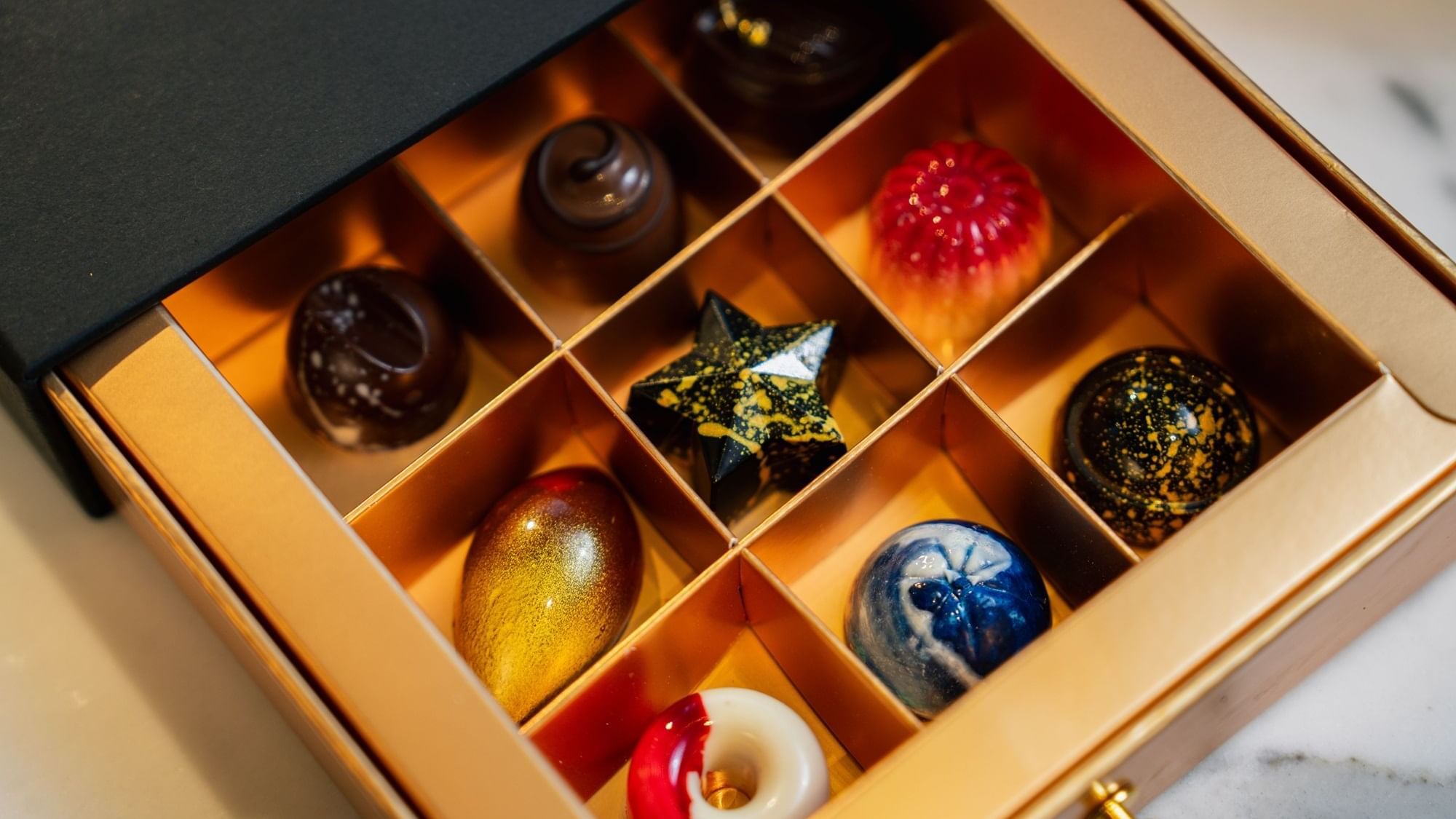 Artistic box of assorted handmade chocolates at the Paramount Hotel Dubai, featuring various shapes and vibrant colors