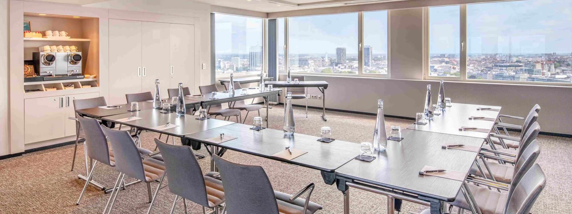 Meet 25 Three Meeting room with tables, chairs, and large windows with a city view at The Hotel Brussels