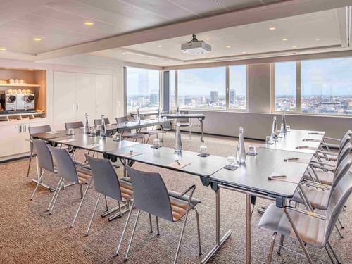 Meet 25 Three Meeting room with tables, chairs, and large windows with a city view at The Hotel Brussels