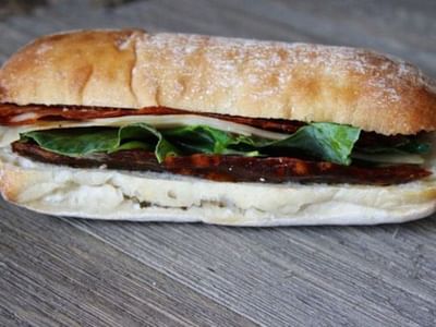 Close-up of fresh sandwich with deli meats, lettuce, and cheese served at Breezeway Boutique Hotel