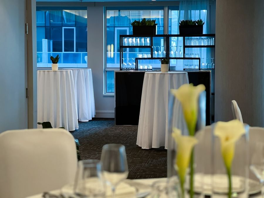 Chic cocktail networking area with white high-top tables and a sleek bar at Warwick Le Crystal Montreal