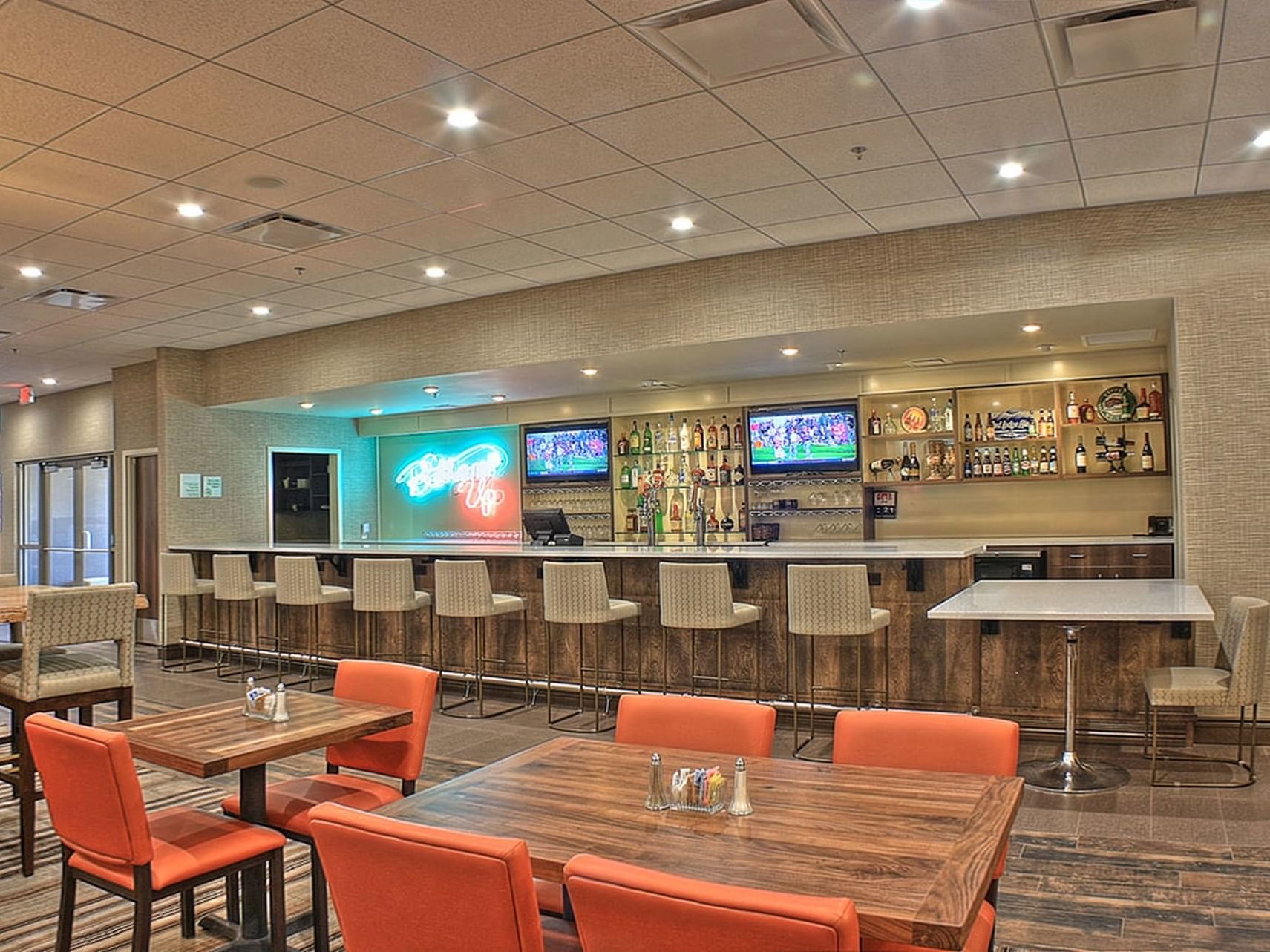 Well-stocked bar and lounge area with glowing neon signs in Bottom's Up Lounge at Blair Hotels.
