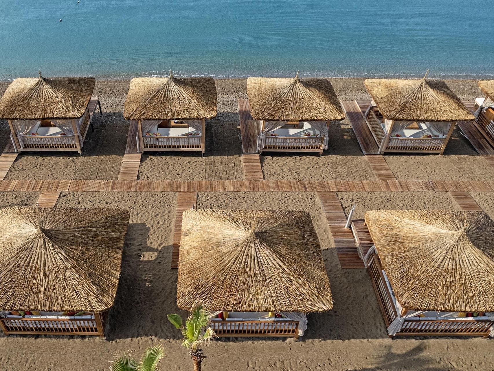 Antalya beachside view of thatched sunshades and loungers at Titanic Deluxe Lara