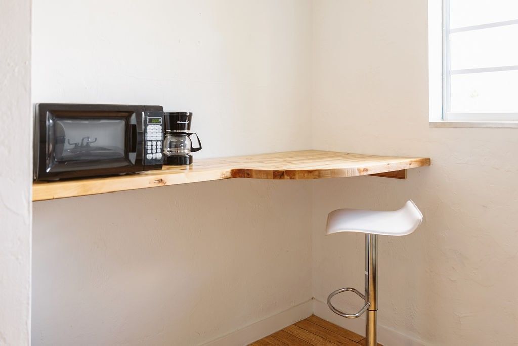 A small kitchenette with a microwave, coffee maker, and desk.