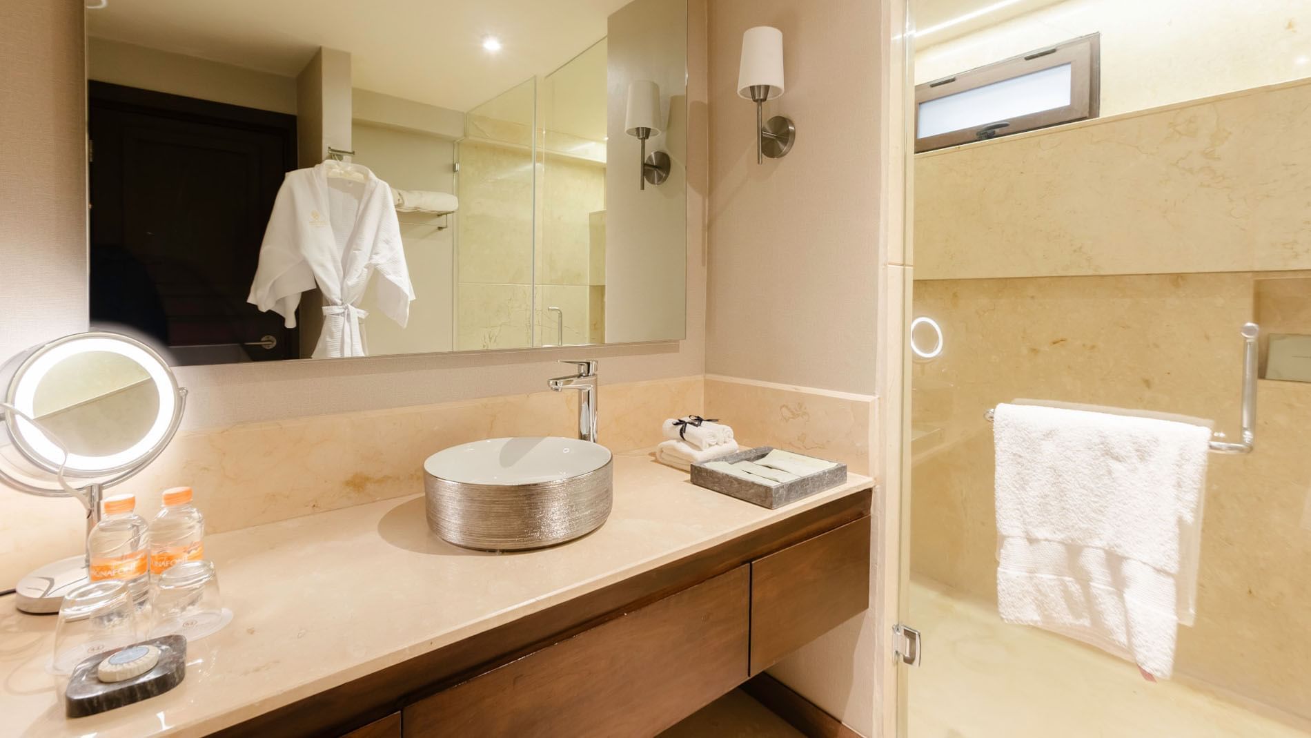Two Double Deluxe bathroom vanity with a silver vessel sink, marble counter, and white robe at Quinta Real Puebla