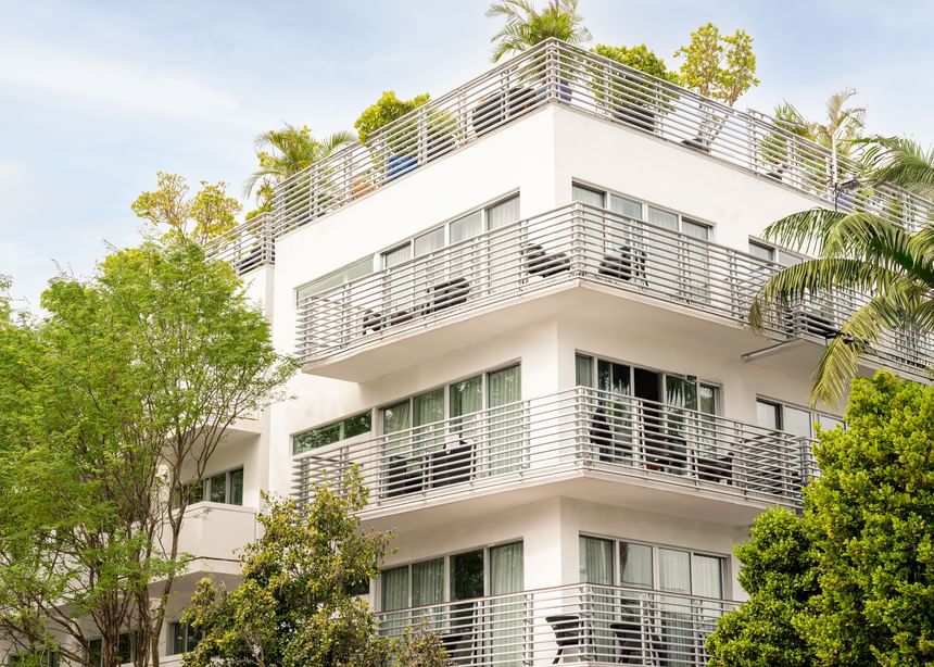 Modern white Riviera Hotel South Beach exterior with wraparound balconies surrounded by lush tropical greenery