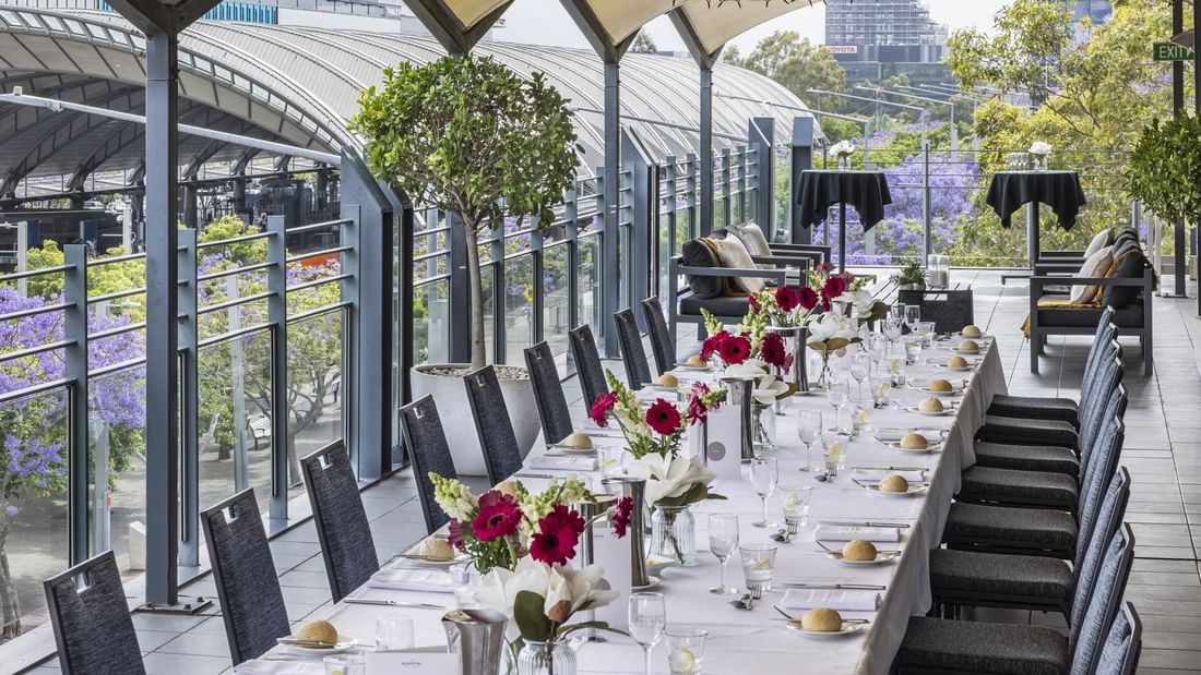 Beautifully set dining table with flowers on Freshwater Balcony, overlooking Accor Stadium at Novotel Sydney Olympic Park