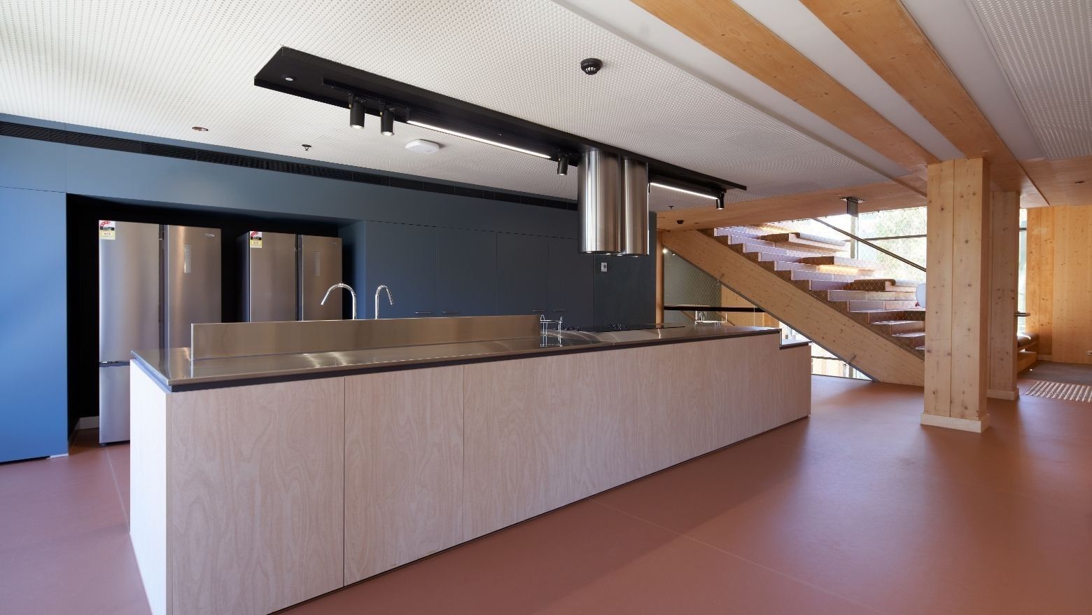 Modern kitchen with blue walls, wooden counter, stainless steel appliances, and adjacent staircase.