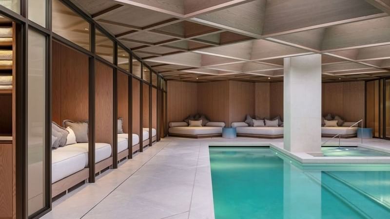 The indoor pool with a lounge area at The Londoner Hotel