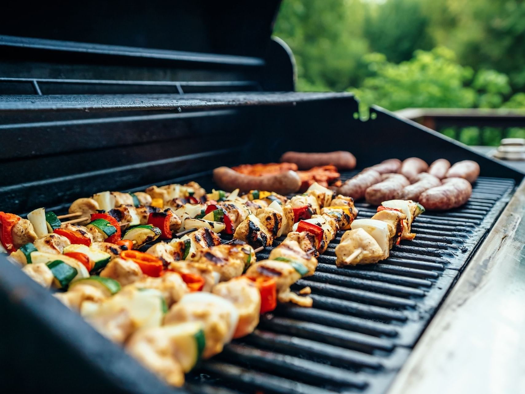 A barbeque grill with meat kebabs, vegetable kebabs and sausages