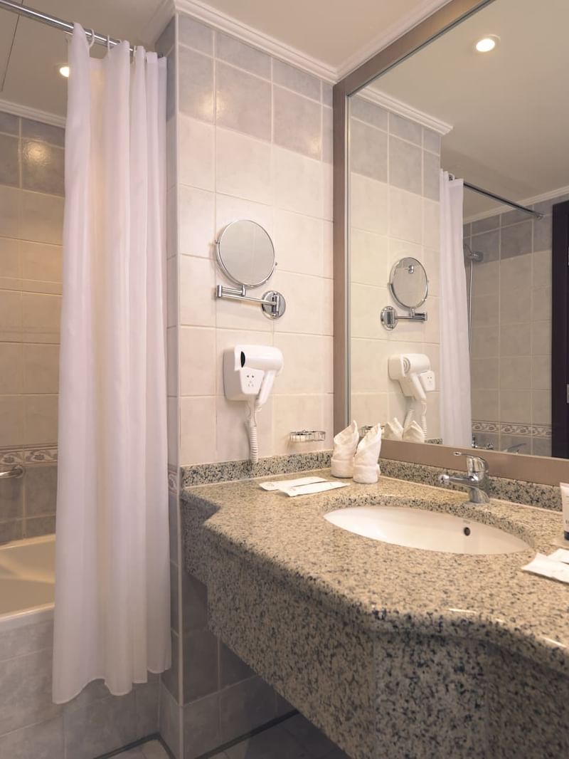 حمام مزود بحوض استحمام ومغسلة ومرآة في غرفة توأم تنفيذية في فندق سجى ورويك المدينة المنورة.