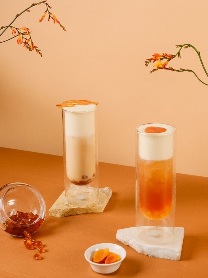 Peach milk tea and caramel milk tea surrounded by flowers and colorful jelly in a jar at Park Lounge, Park Hyatt Saigon