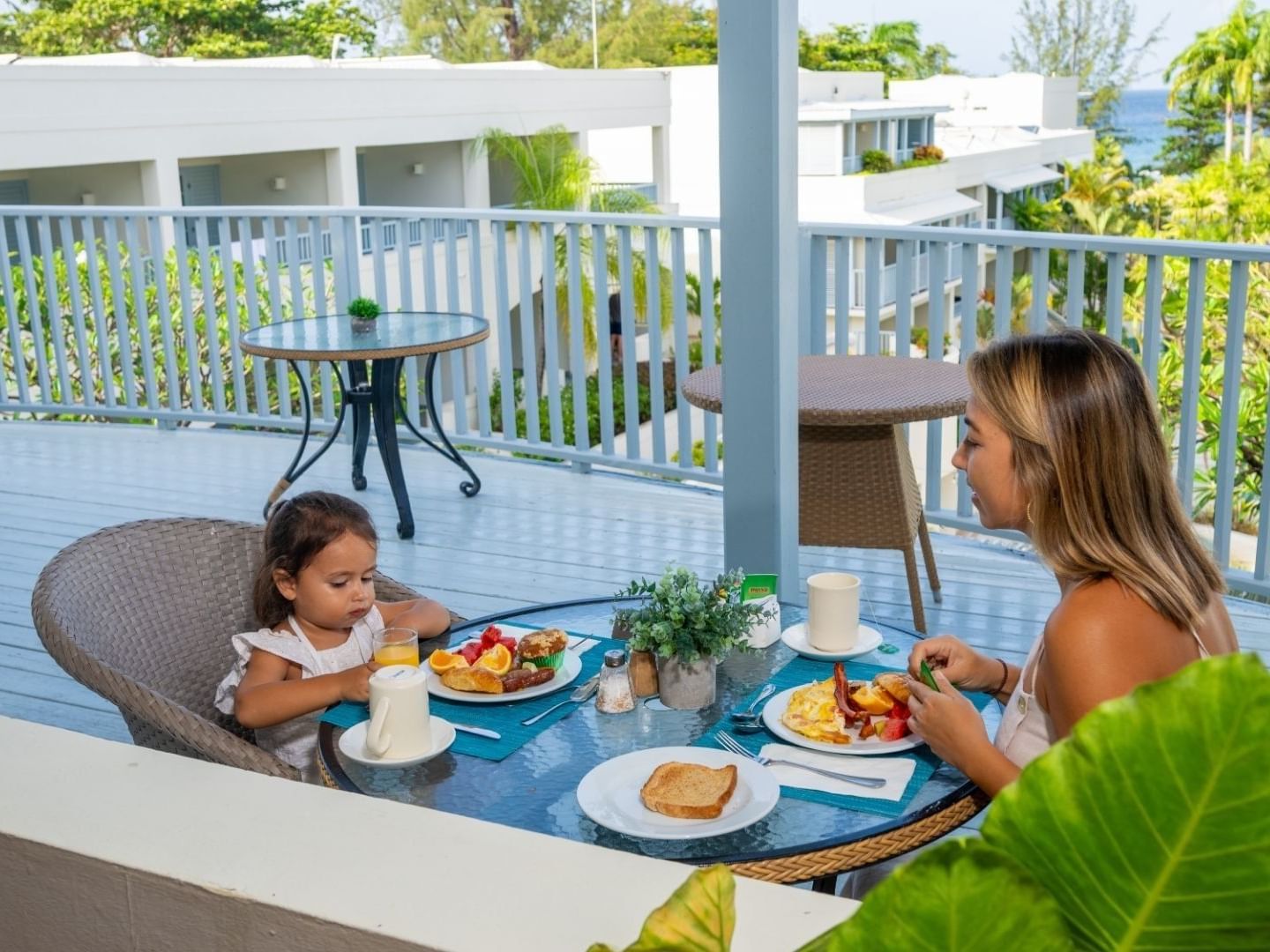 Woman and child eating breakfast at a beachside table at Savannah Beach Hotel.