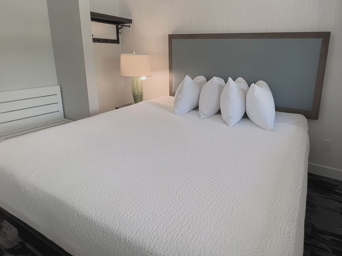 Guest bedroom with King ped, four pillows, a lamp, side table and window view