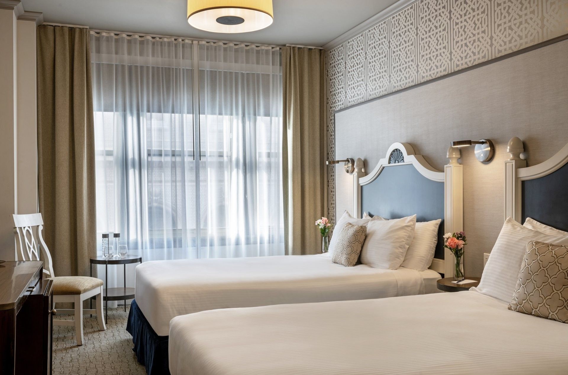 Round table by a white chair and tan curtains under a hanging lamp in Deluxe Queen Room at Warwick San Francisco