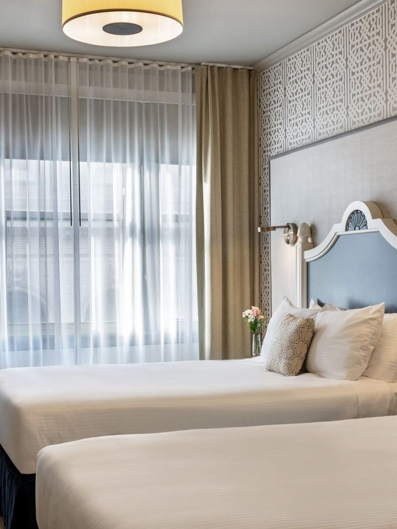 Twin Room features Two beds by a wooden desk under drum pendant lights at Warwick San Francisco