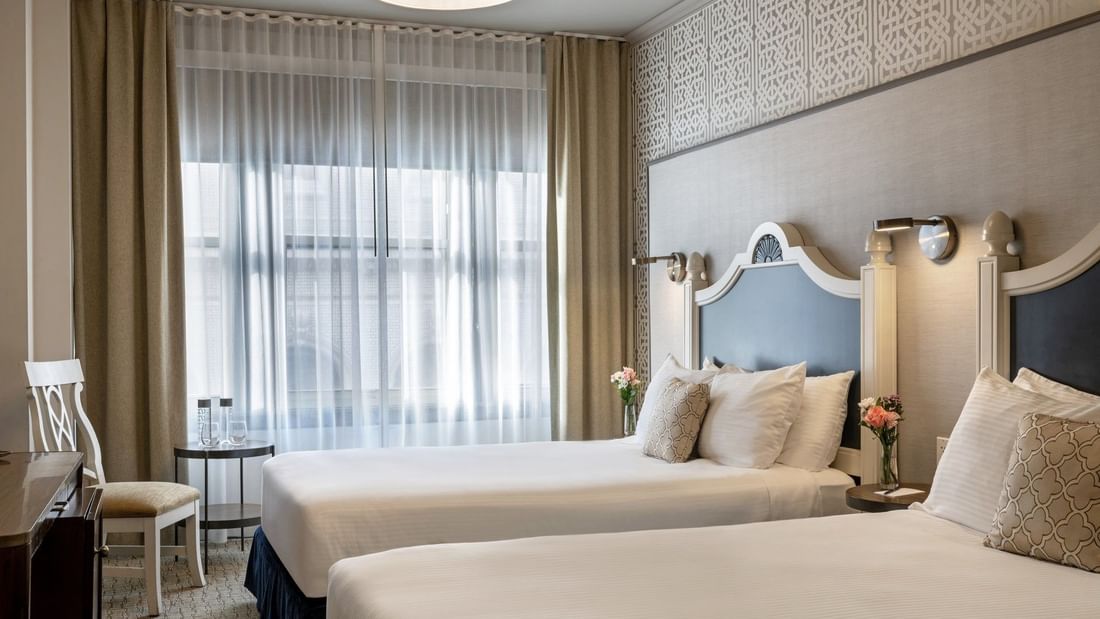 Twin Room features Two beds by a wooden desk under drum pendant lights at Warwick San Francisco