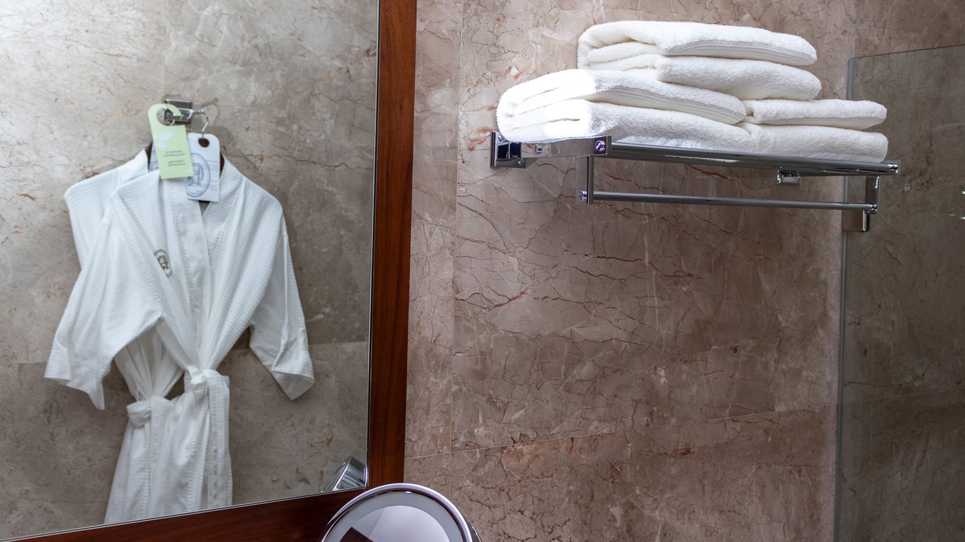 Towels and white bathrobe in the bathroom mirror reflection at Quinta Real Oaxaca