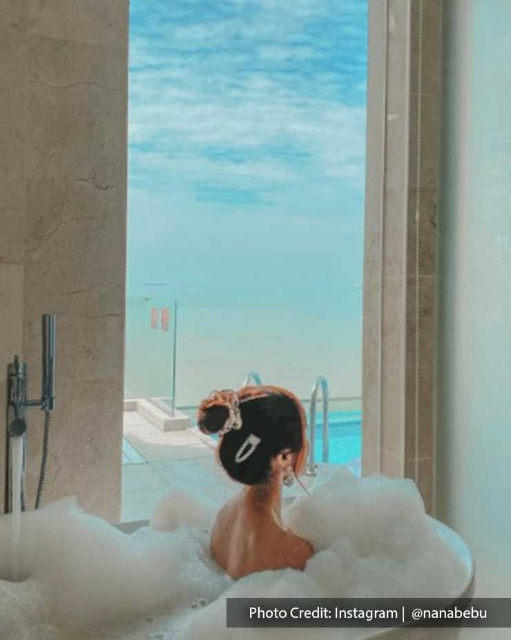 Woman in bubble bath in bath tub in Lexis Hibiscus