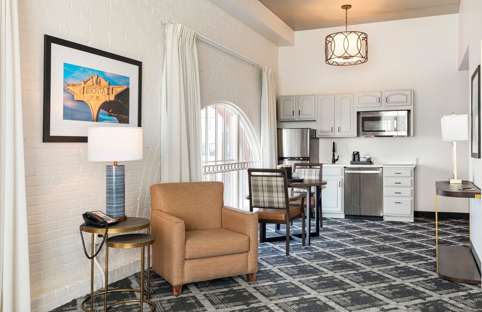 A wide view of a hotel suite's living area, kitchenette, and dining area