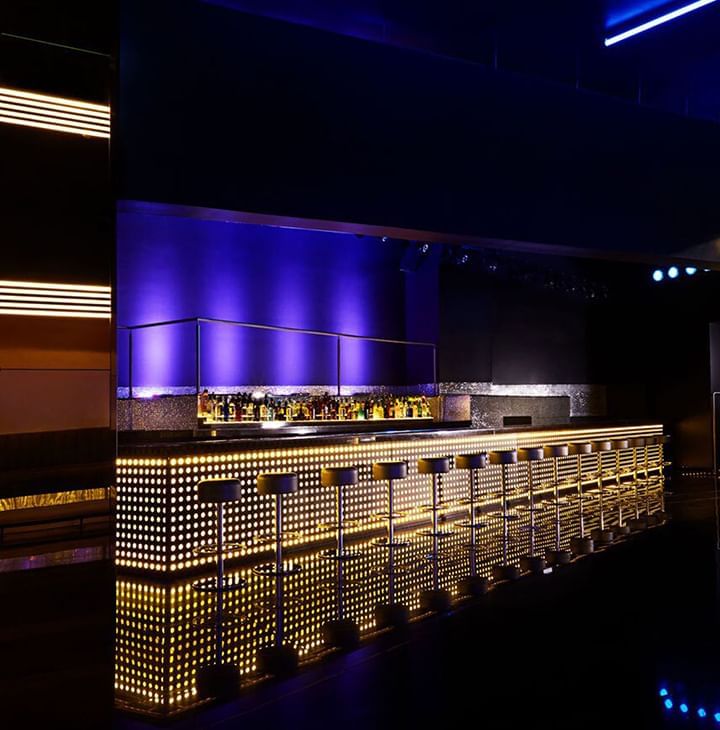 Bling bar with stools lined by a glowing gold counter, under purple lighting and neon panels at Megapolis Hotel Panama