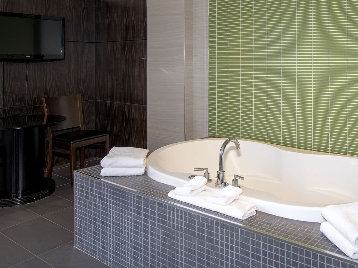 A hotel suite with soaker tub and a TV mounted on the wall.