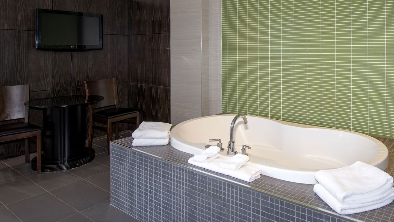 A hotel suite with soaker tub and a TV mounted on the wall.