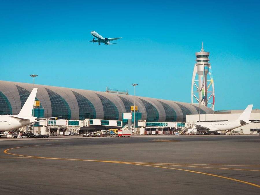 Dubai Airport terminal with planes and a control tower near DAMAC Hotels & Resorts, a 5-star hotel in Dubai