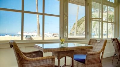 Coastal view from a sunlit room with rattan chairs and table at Pavilion Hotel