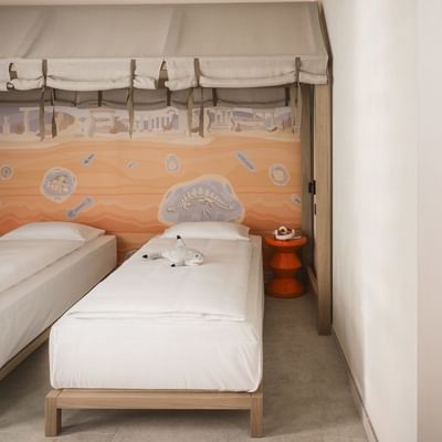 Due letti sotto una tenda, un bagno con un murale egiziano, e un bagno con un lavabo e uno specchio.