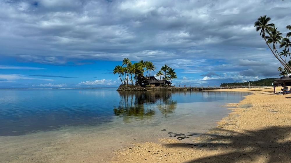 Sandy beach view with palm trees and ocean at Warwick Fiji Resort and Spa Korolevu.