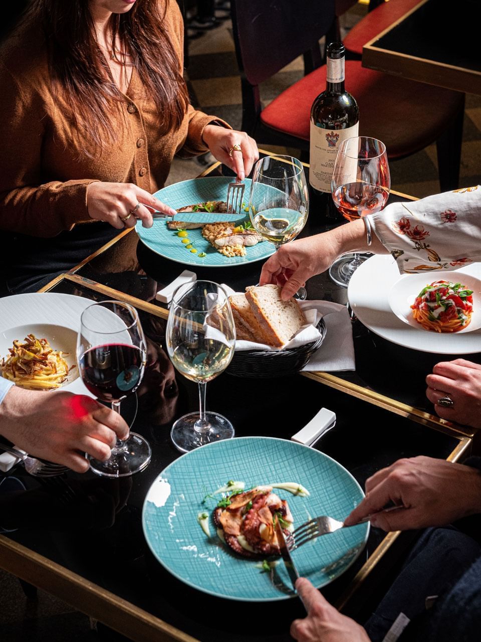 A group enjoys a lavish meal with assorted dishes, wine, and fresh bread on a stylish dining table at The Guardian Hotel