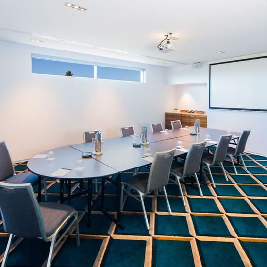 Boardroom set up for conference with projector screen at Pullman Magenta Shores