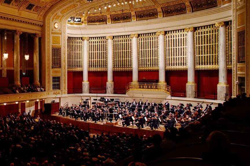 Concert hall of the Wiener Orchesterwelt featuring a large symphony orchestra on stage and elegant gold decorated interior architecture