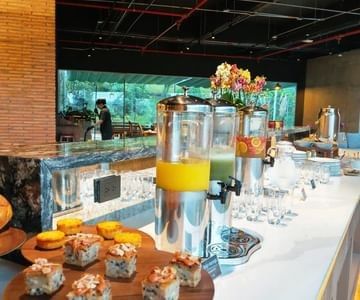 Breakfast buffet with juice dispensers by pastries and glasses under pendant lights at Unika Hotels, Restaurant Bogota