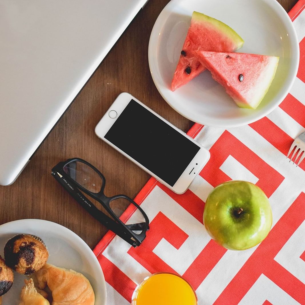 Fruits, baked goods & phone on table at Cyan Soho Neuquen Hotel