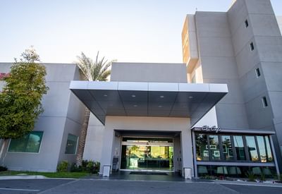 Entrance of Hotel Mirra with gray facade, covered canopy and glass doors best hotel in san luis rio colorado for work trips