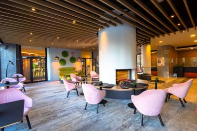 Lobby area with chairs, tables, fireplace and decorative wall art at Metropol Hotel