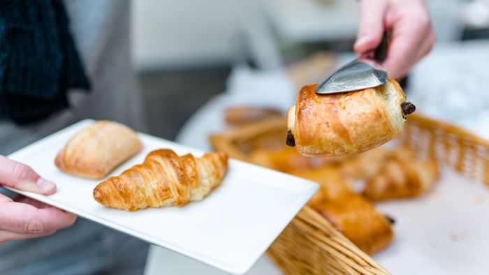 A waiter serves pastries to a plate at Ara hotel