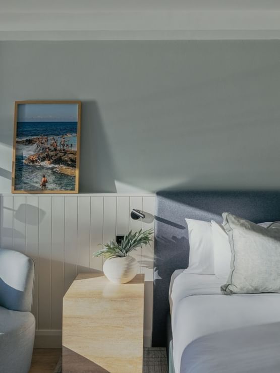 Ocean View Two Bedroom at Elysium Hotels bed with framed coastal art and a plant beside a wooden nightstand