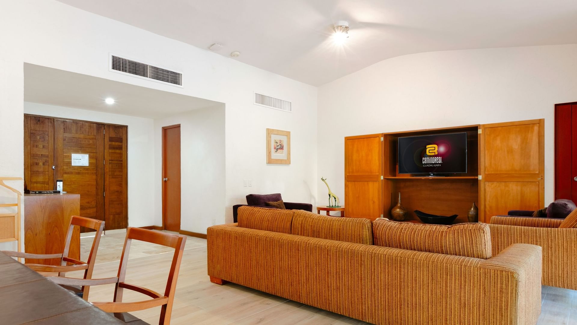Spacious King Real Suite with a large couch, wooden furniture, and flat-screen TV at Camino Real Guadalajara in Zapopan