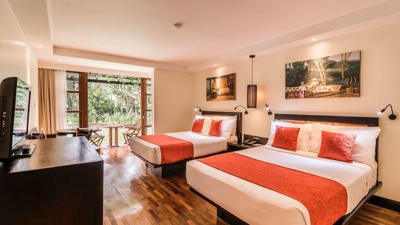 Red-accented beds by a dark console under framed art in Superior Garden View Rooms at Warwick Fiji Resort and Spa