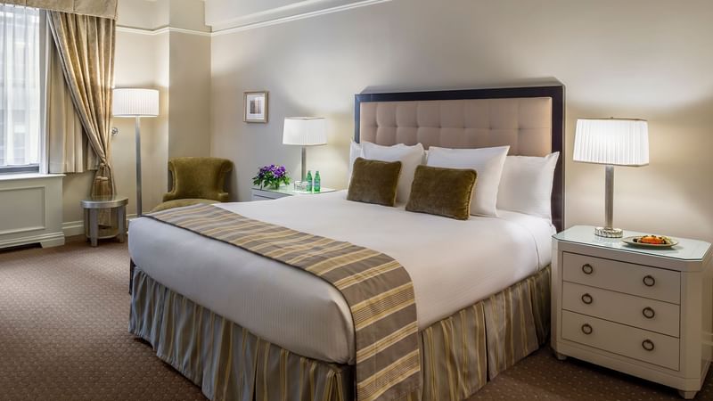 Comfy bed with side tables and chair in Junior Suite at Warwick New York