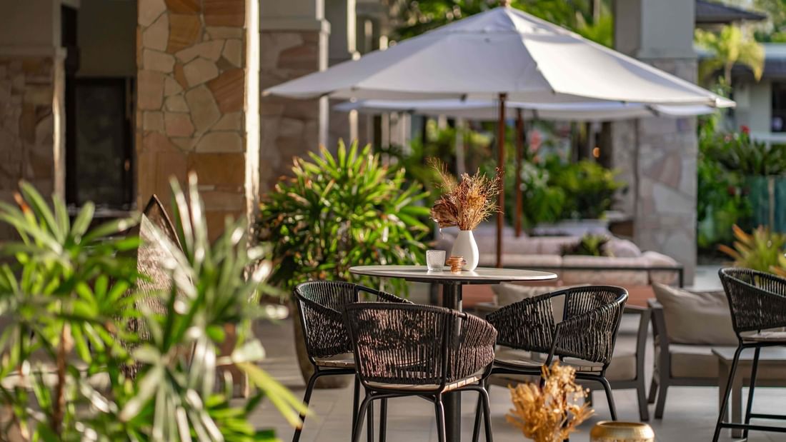 Outdoor setting with wicker chairs and marble table with vase in Lagoon View Terrace at Pullman Port Douglas