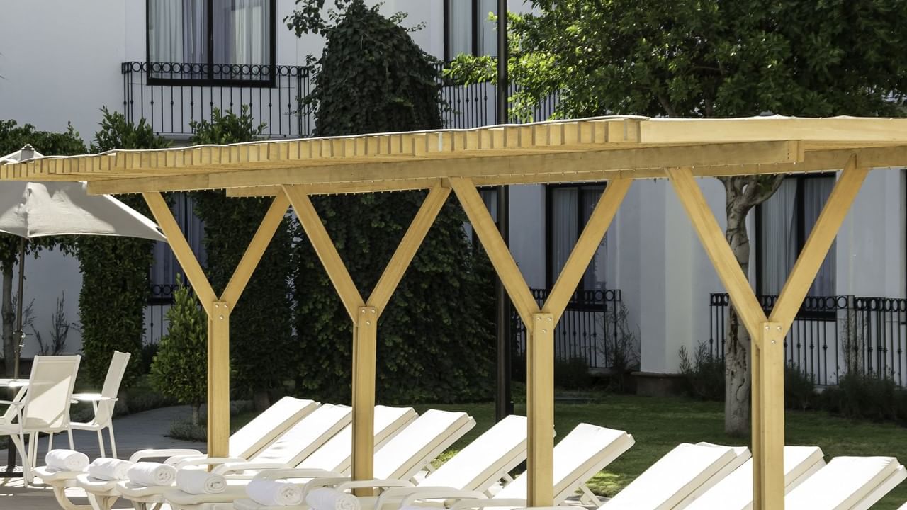 A row of sunbeds by the outdoor pool at Fiesta Inn Querétaroro