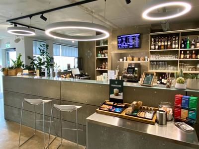 Café interior featuring a counter, illuminated rings, and shelves stocked with drinks and snacks at Avaneo Hotel