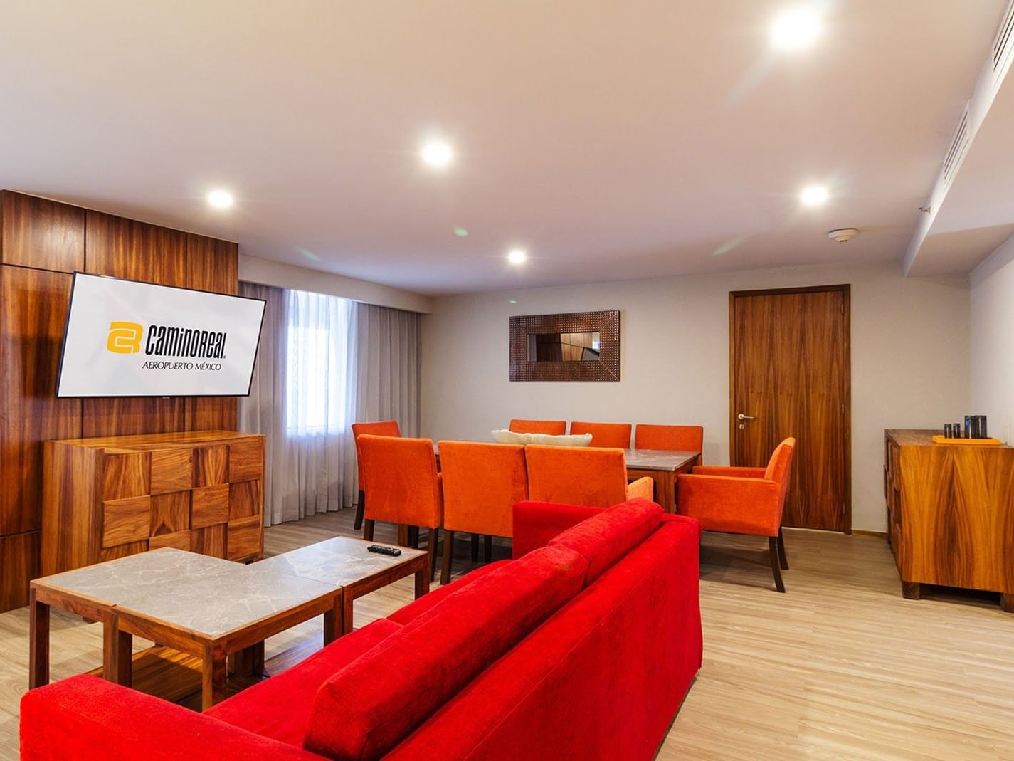 Salón elegante con sofá rojo y mesa de comedor en Master Suite King de Camino Real Aeropuerto México en Ciudad de México