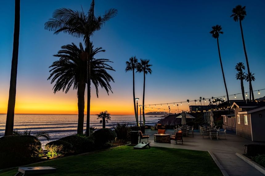 Hotel terrace fire pit with seating at sunset on the ocean 