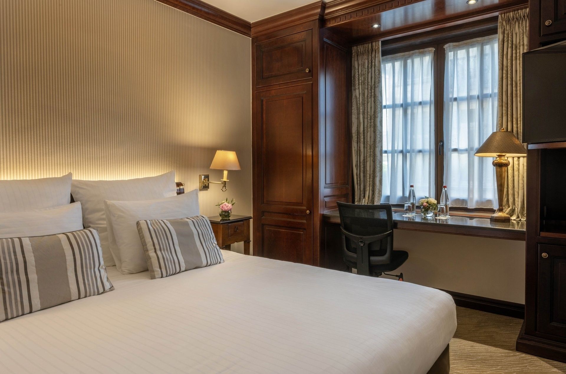 Bed with a wood cupboard and a working desk near window in Classic Room at Warwick Grand Place Brussels