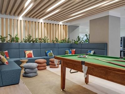 Modern recreation lounge with pool table, sectional seating, and wooden slatted ceiling at UniLodge Auckland Central